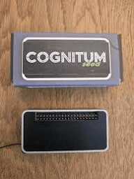 The Cognitum One Seed — small dark module shown next to its retail box branded COGNITUM seed.